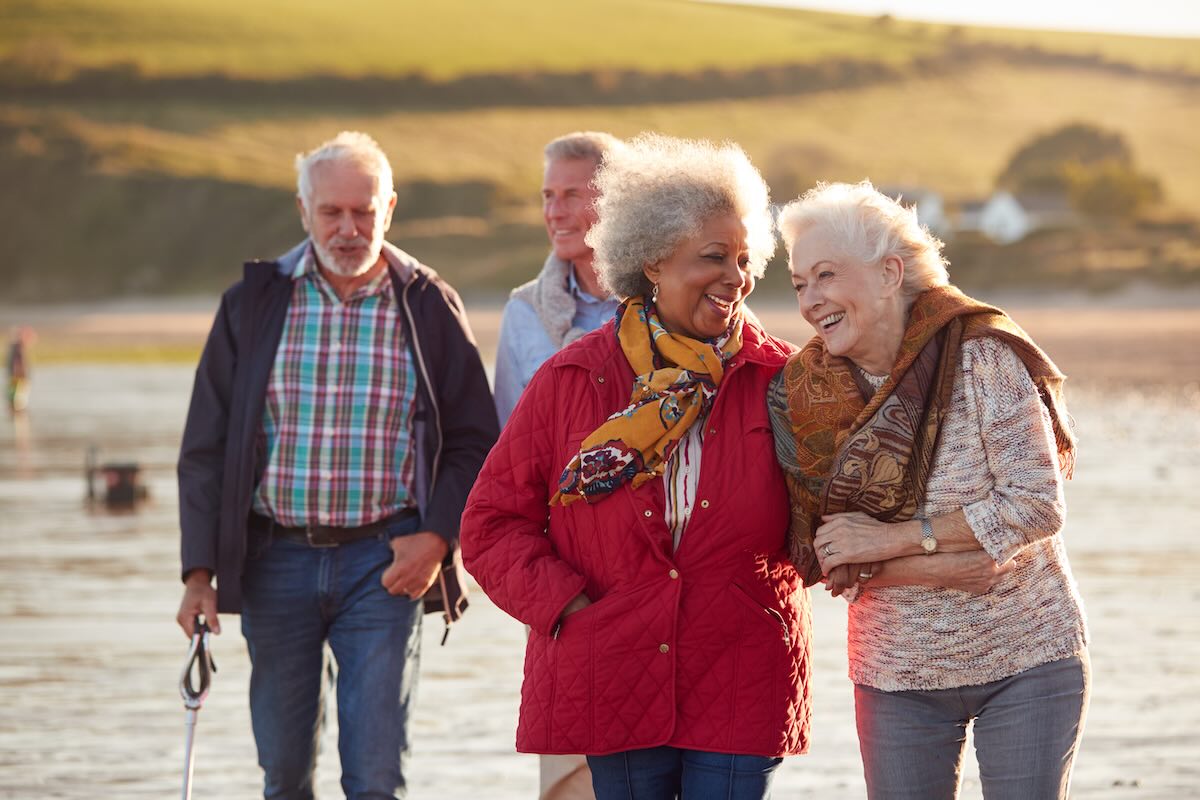 4 seniors walking down a beach 